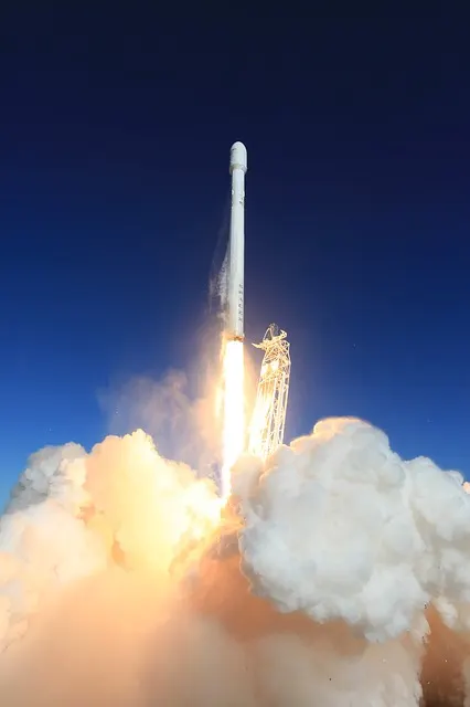 A rocket climbing into a dark blue sky trailing a bright exhaust plume