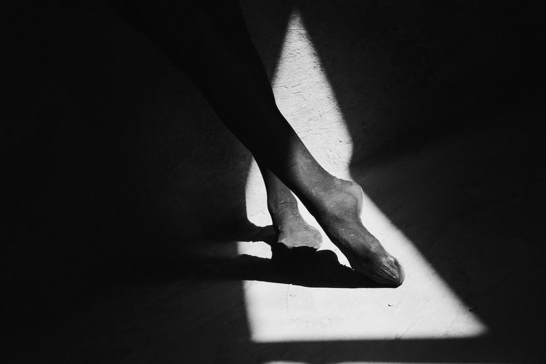 Free Faceless ballerina resting on floor with shade Stock Photo