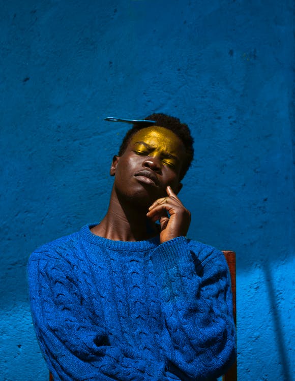 Free Man in Blue Knit Sweater Against Blue Wall Stock Photo