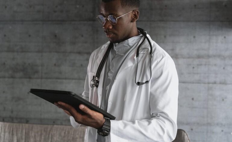 Free Man in White Coat Holding Black Tablet Computer Stock Photo