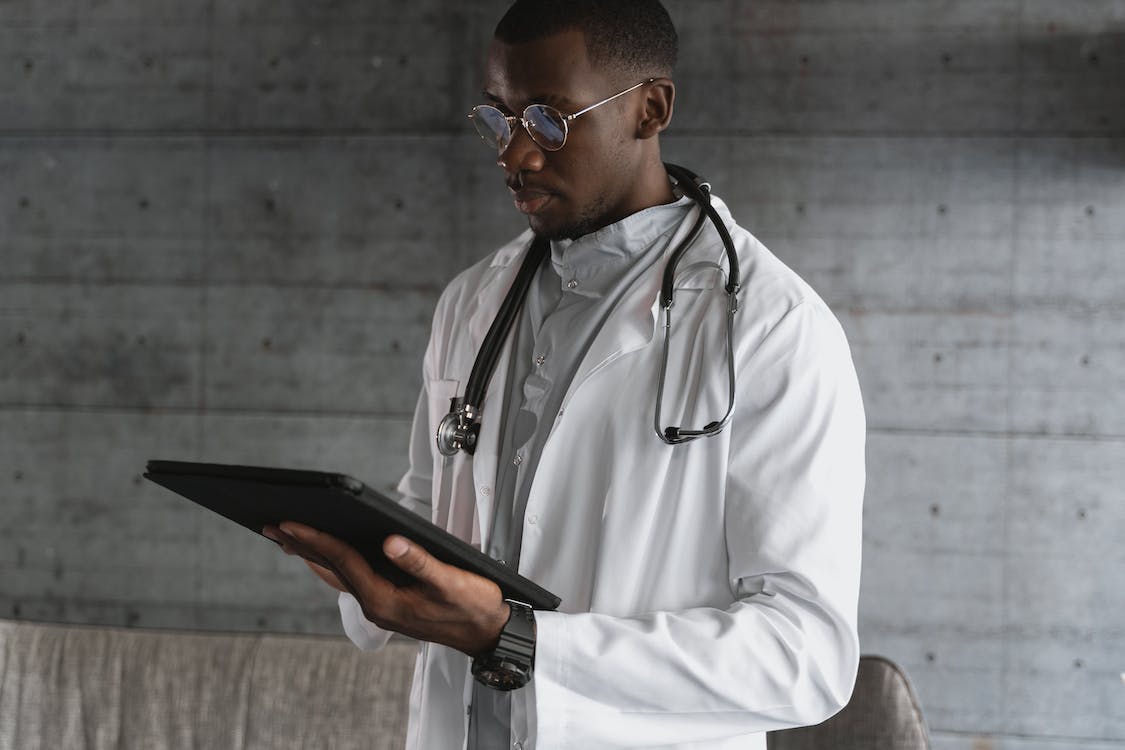 Free Man in White Coat Holding Black Tablet Computer Stock Photo