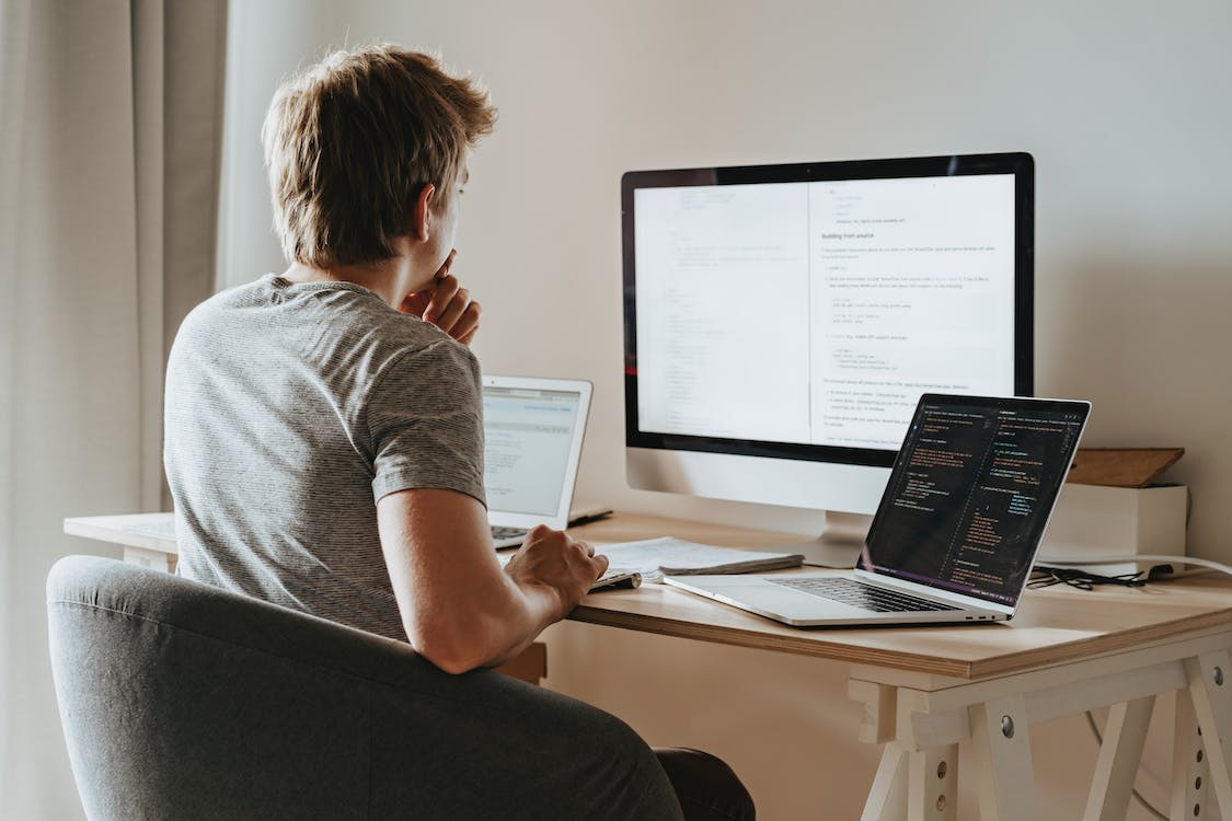 Free Man Sitting in Front of Three Computers Stock Photo