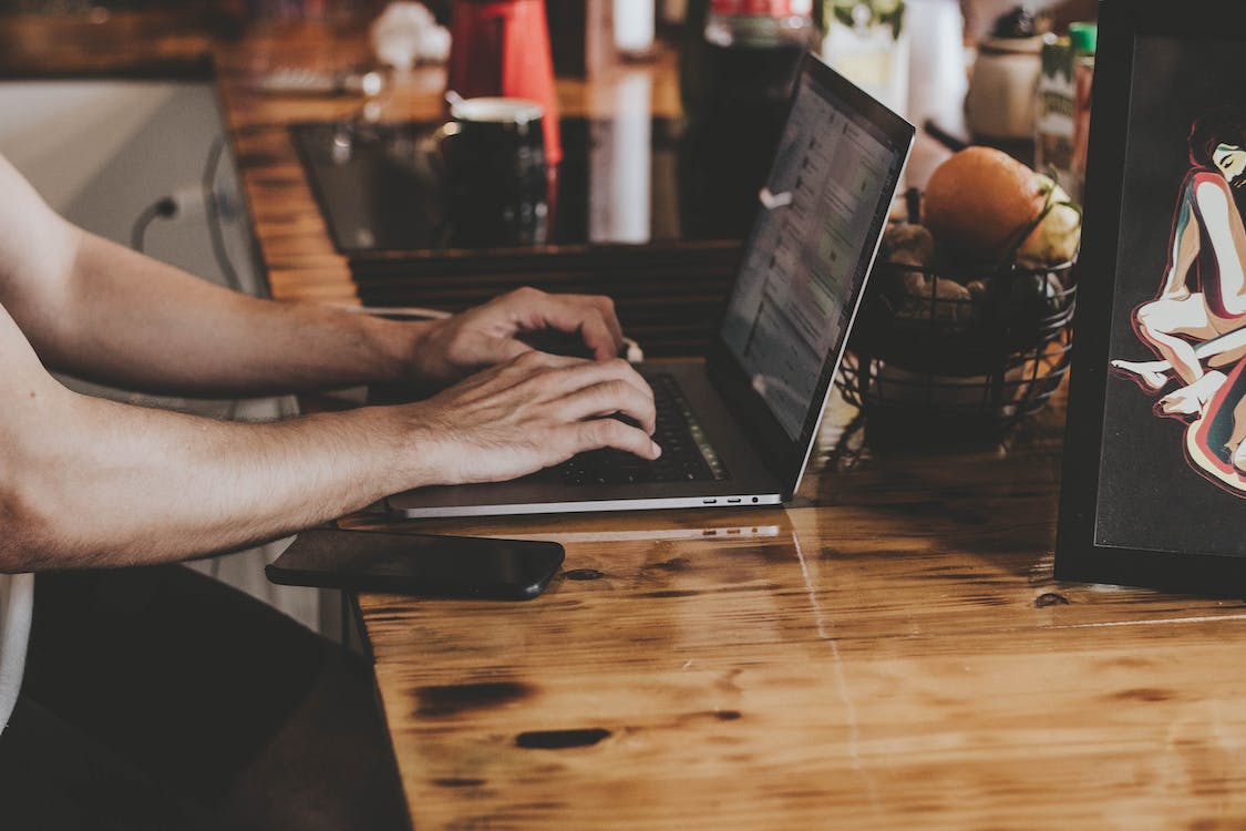 Free Person In Front Of Laptop On Brown Wooden Table Stock Photo