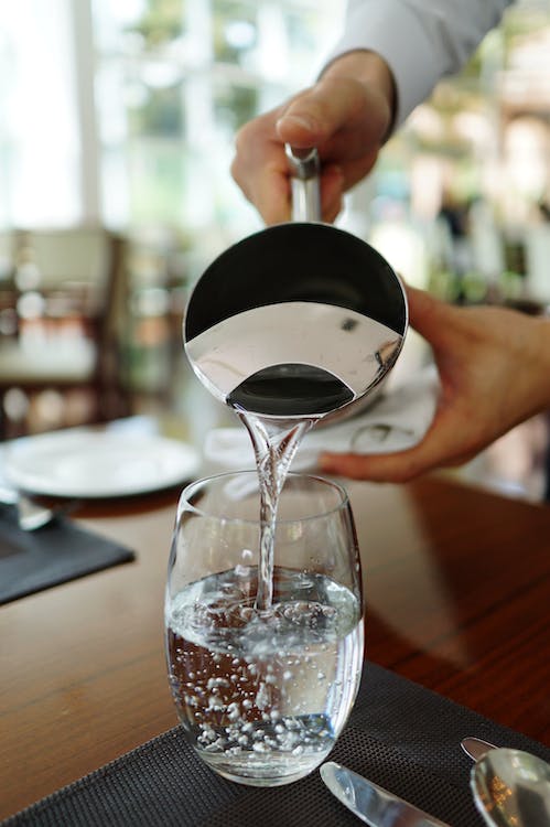 Free Person Pouring Water on Glass Stock Photo