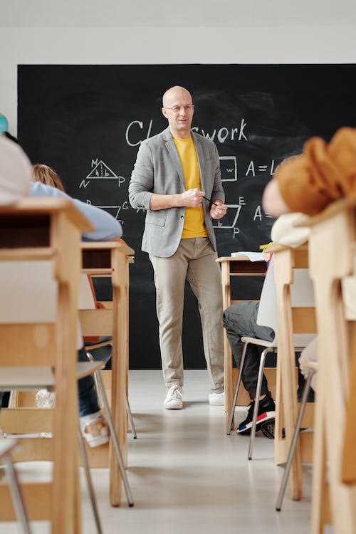 Free Teacher Standing in Front of a Blackboard Stock Photo