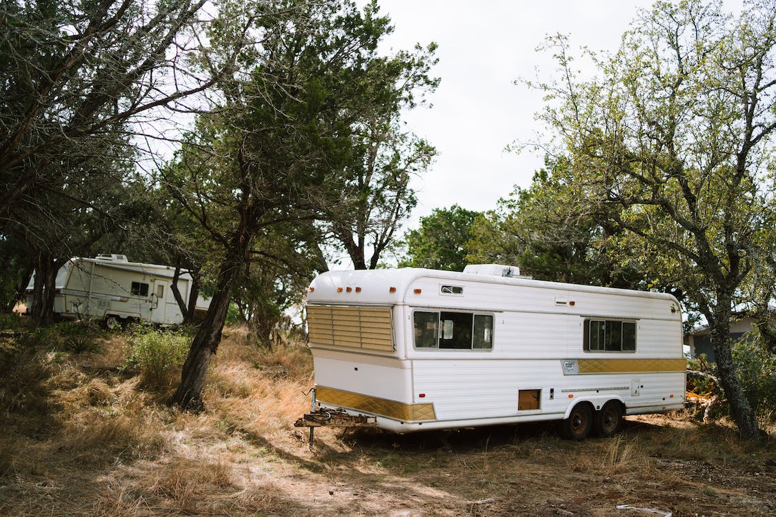 Free White and Brown Rv Trailer Near Green Trees Stock Photo