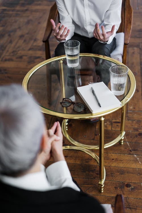 Free Woman in Black Long Sleeve Shirt Sitting on Brown Wooden Chair Stock Photo