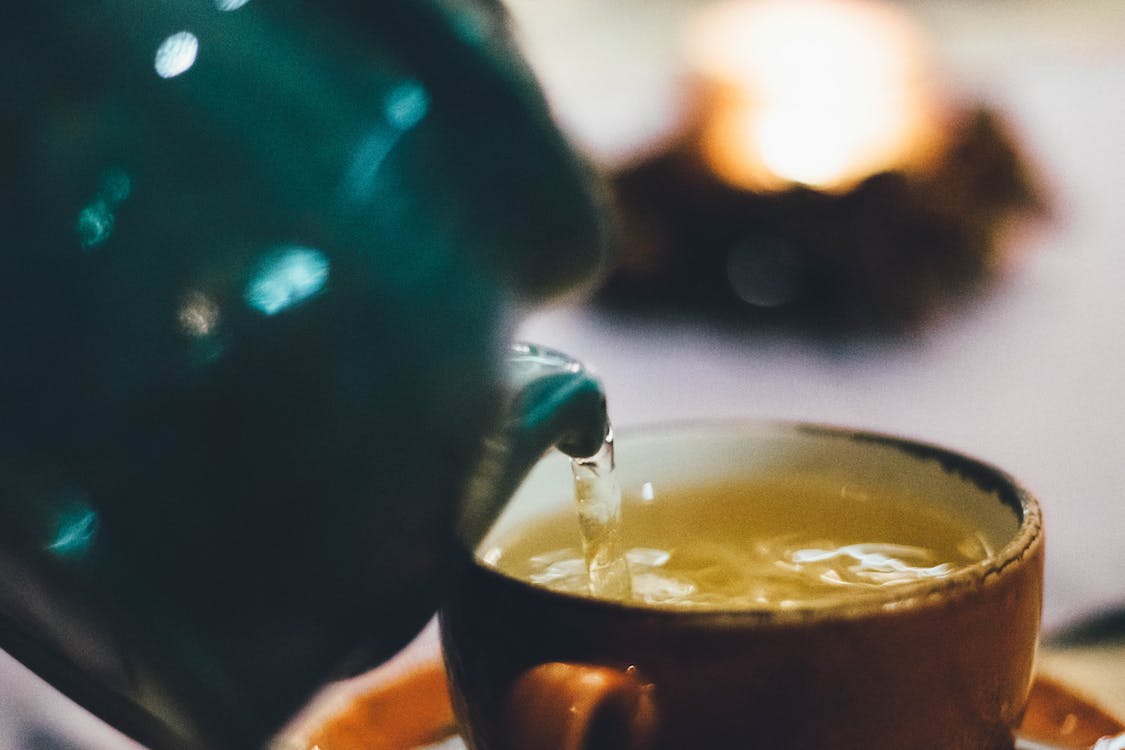 Free Person Pouring Liquid Into Brown Ceramic Cup Stock Photo