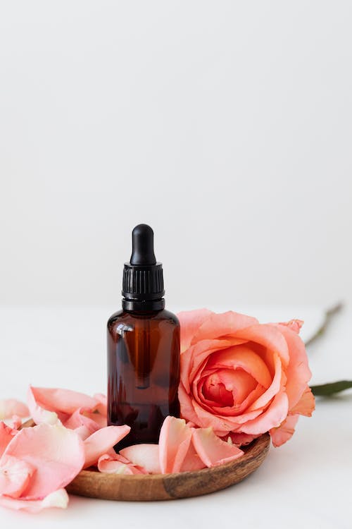 Free Set of cosmetic bottle with pink rose on wooden plate Stock Photo