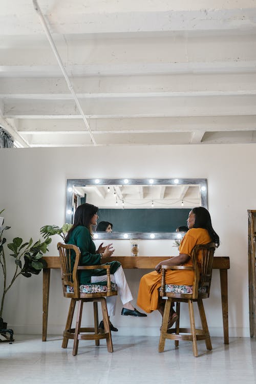 Free Two Women Sitting on Wooden Chairs Stock Photo