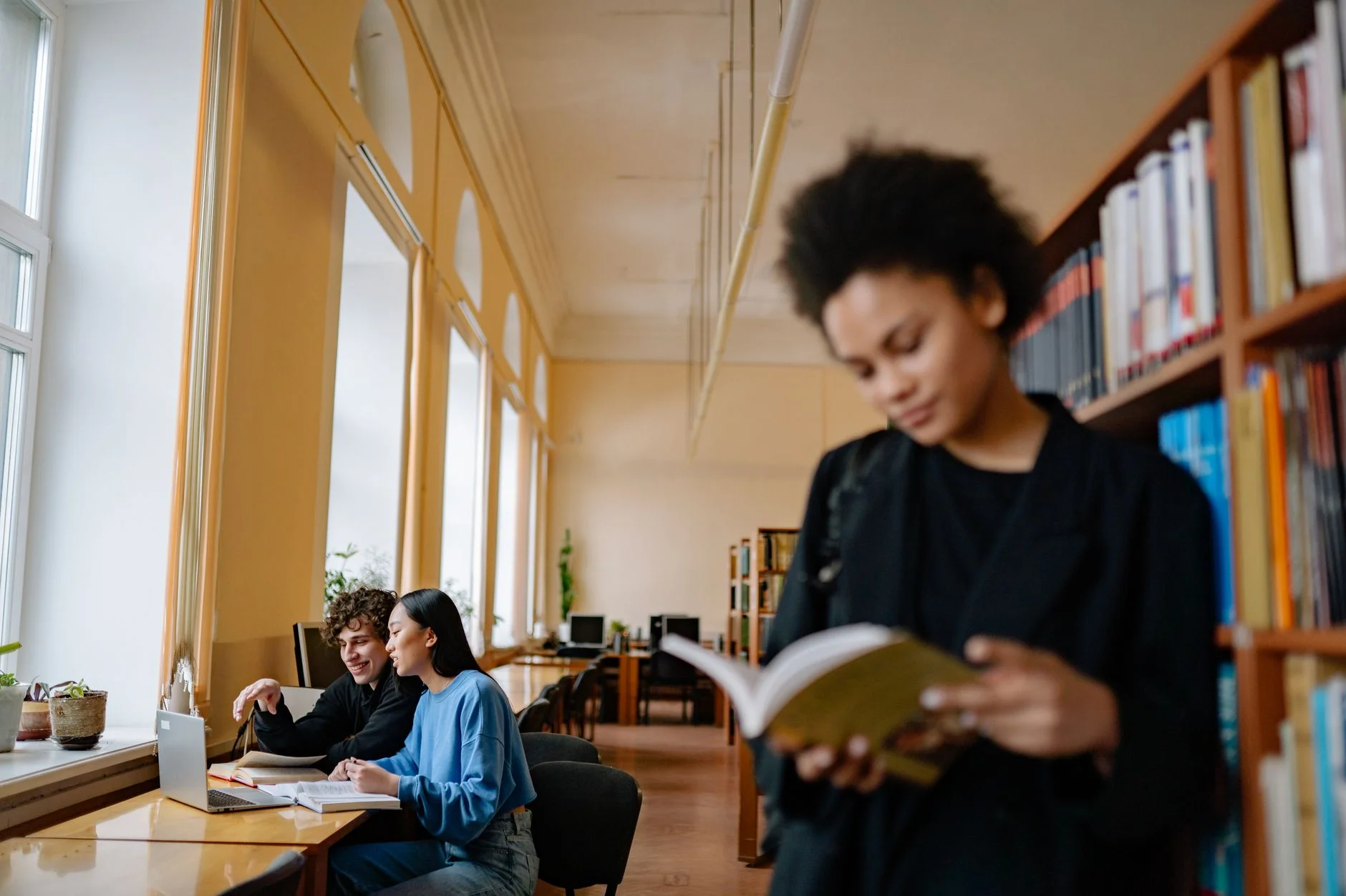 University students studying with books and laptops in a library