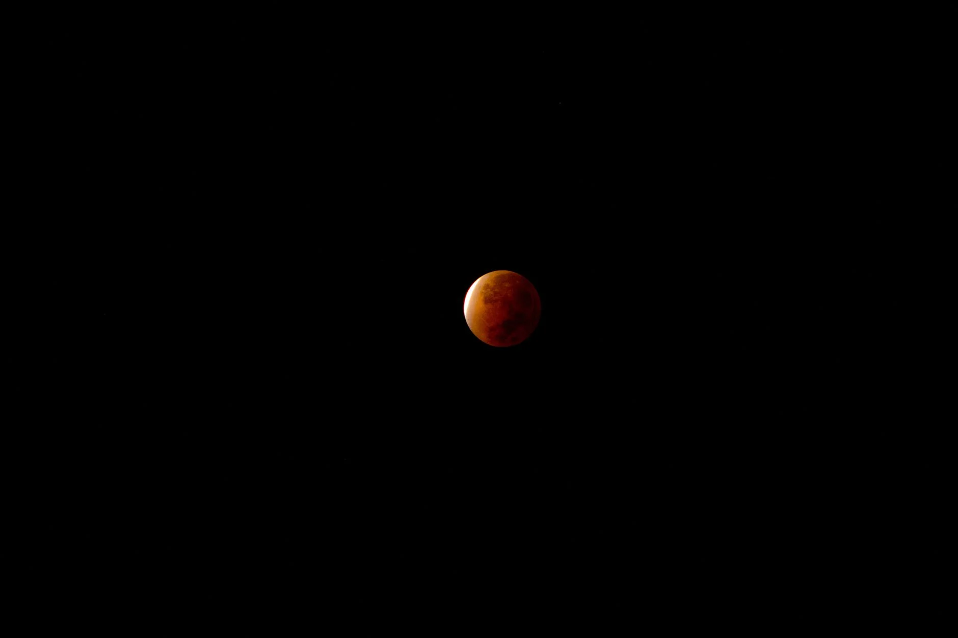 Red blood moon during a total lunar eclipse against a black sky