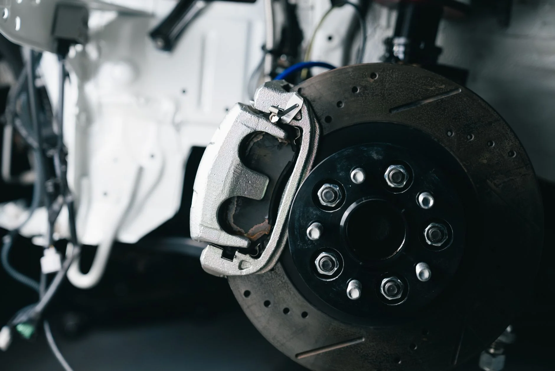 A car brake disc with the brake calliper fitted, seen with the wheel removed