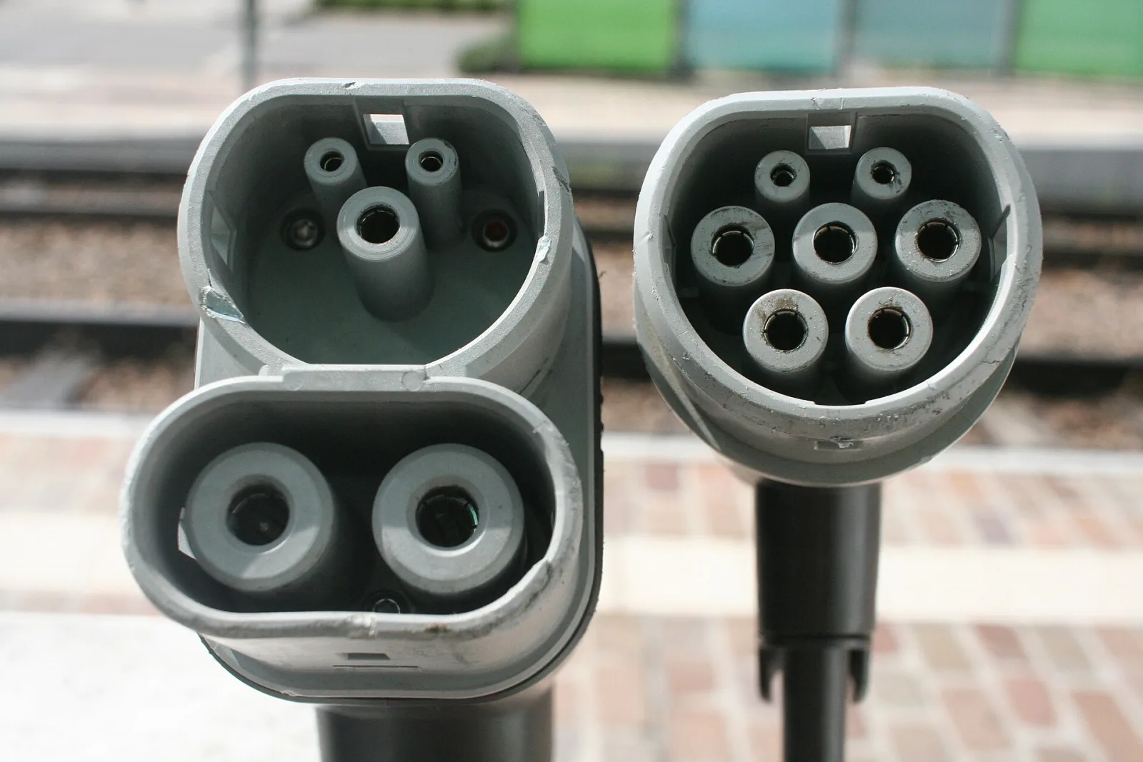 Two grey charging plugs side by side: a CCS plug with two large DC pins below the round section, and a seven-pin Type 2 plug