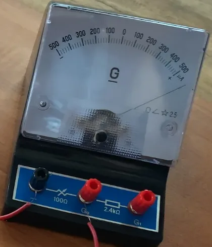 Close-up of a centre-zero galvanometer with a 500–0–500 microamp scale, needle deflected towards the plus side, terminals marked 100 ohm and 2.4 kilohm