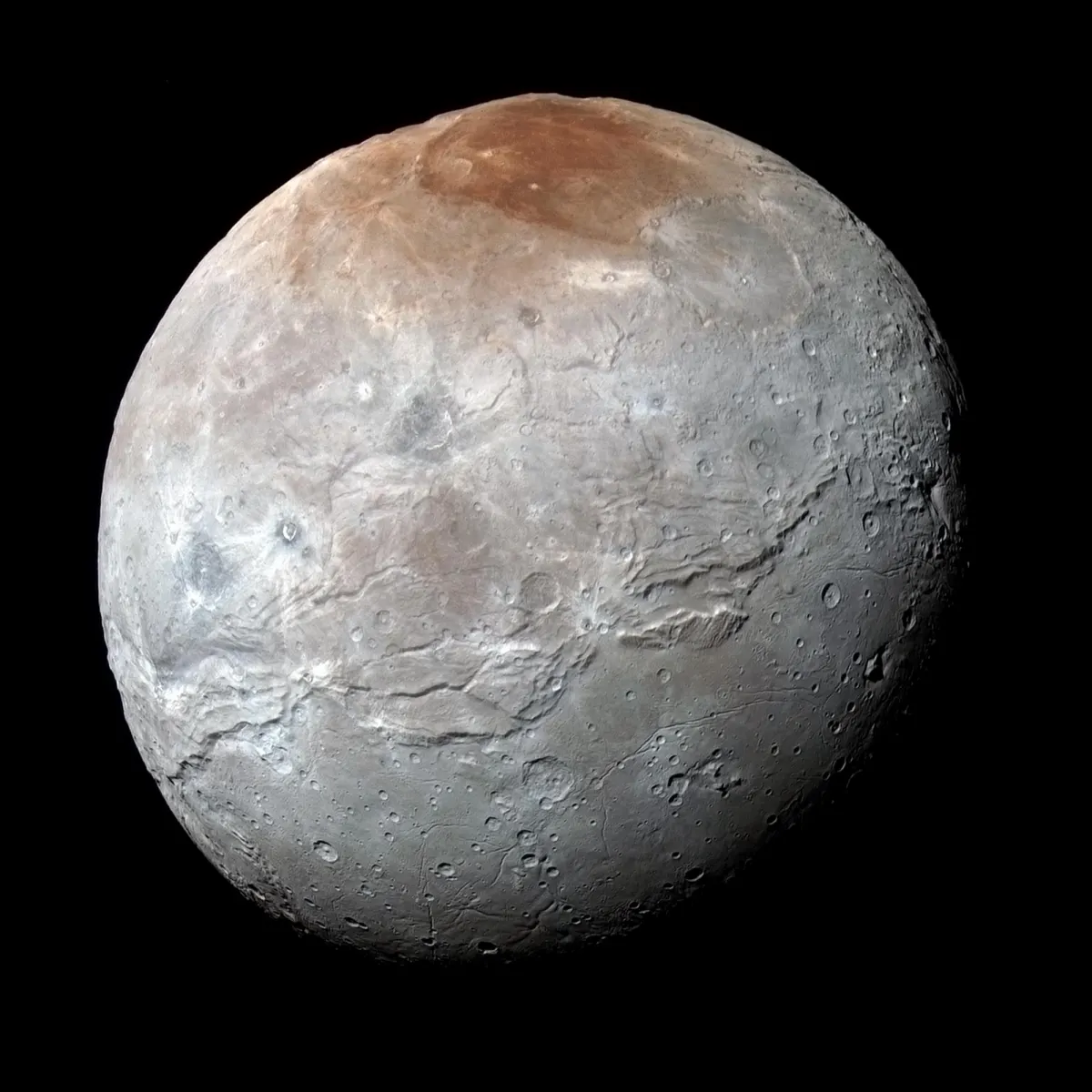 Charon, Pluto’s largest moon, in enhanced colour from New Horizons, with a reddish north polar region