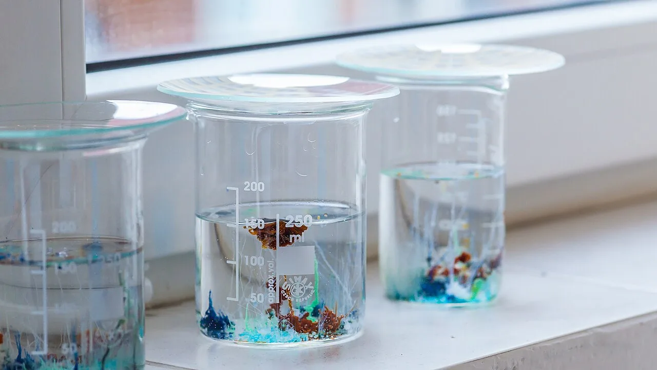 Three beakers of sodium silicate solution with blue and brown chemical-garden growths