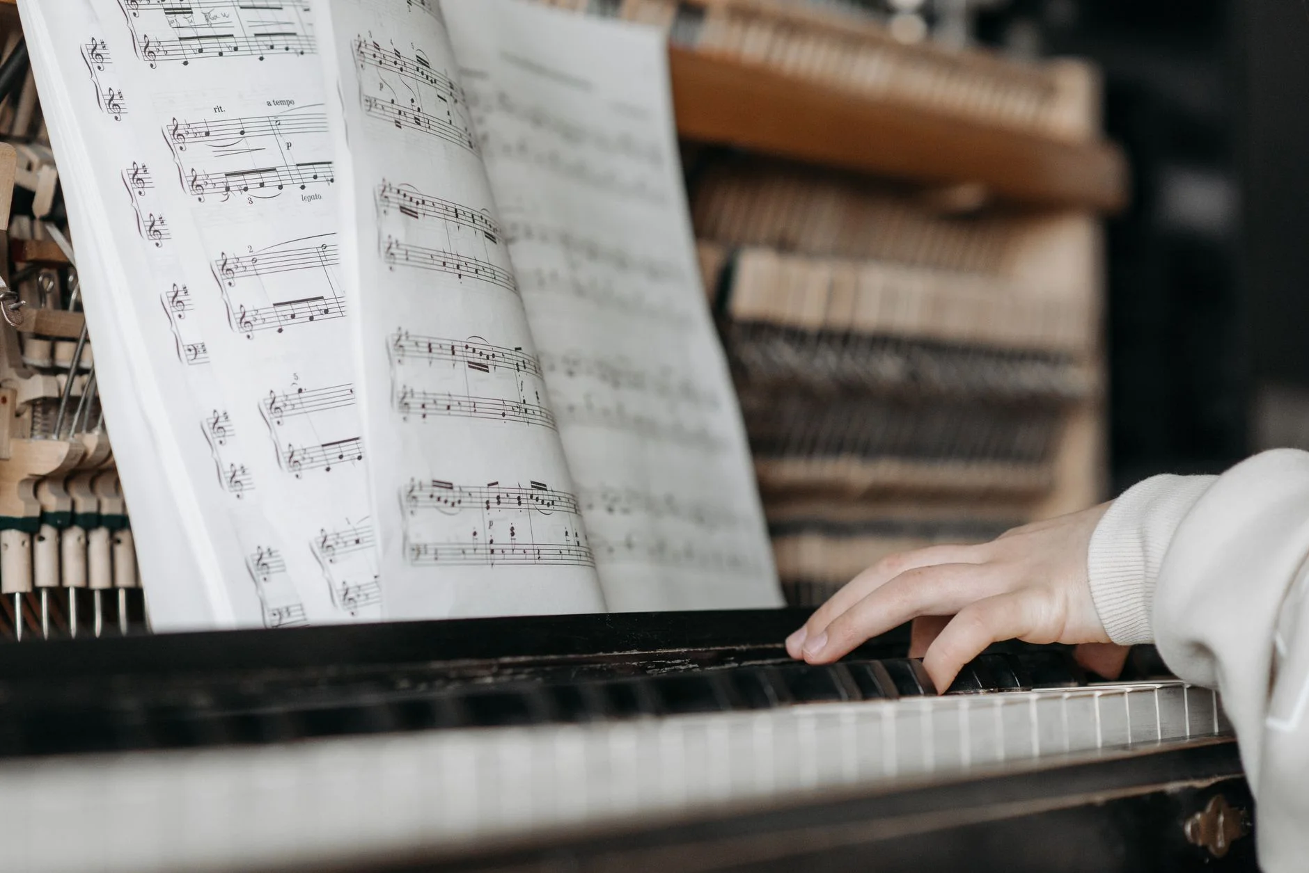 Open sheet music on a piano with a hand on the keys