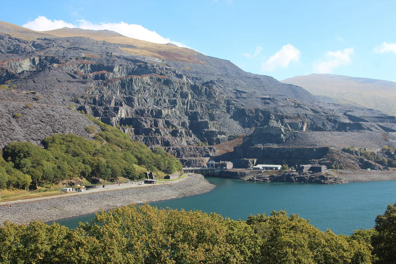 Terraced slate quarry above a blue lake in Snowdonia, with the Dinorwig power station buildings at the water’s edge