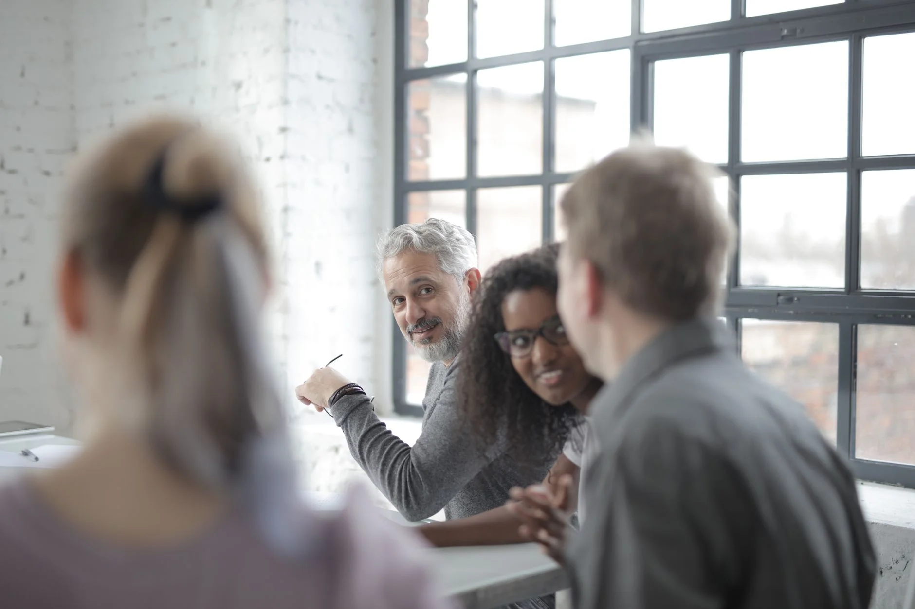 Colleagues of different ages chatting around a table in a bright office
