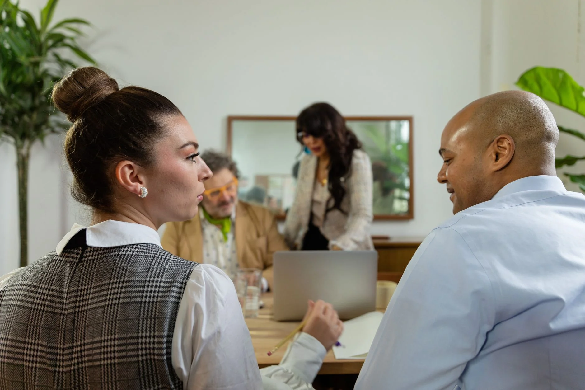 Colleagues talking around a table with a laptop in a bright office