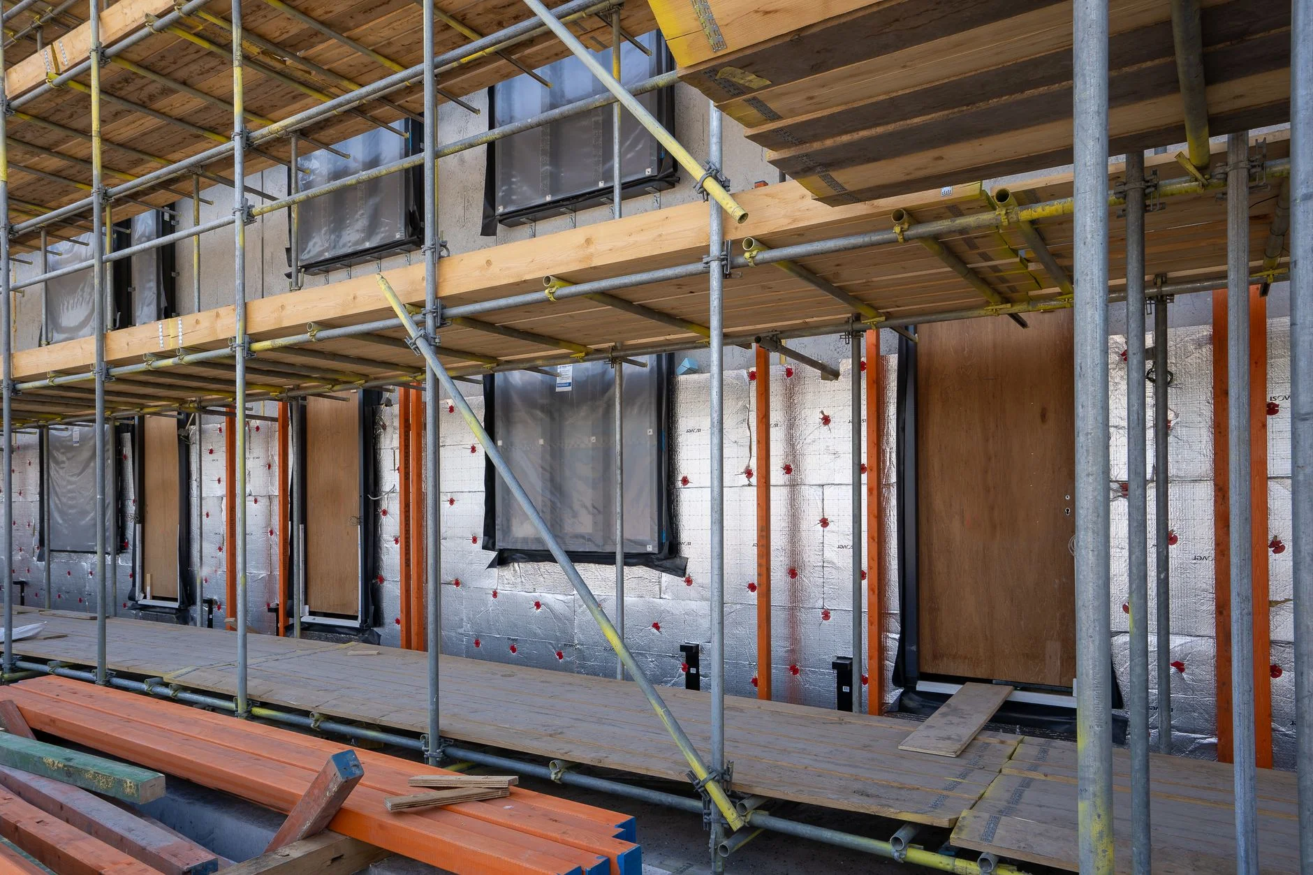 Scaffolding in front of a building with insulation sheets fixed to the outer wall around the window openings