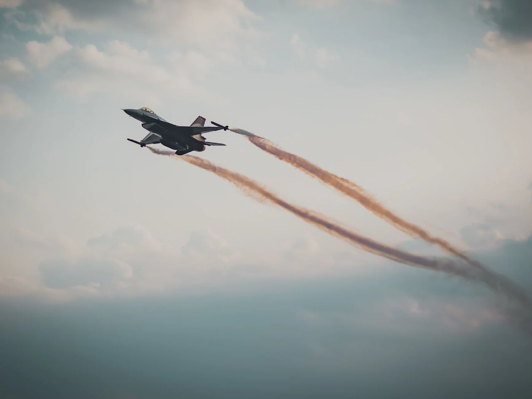 Military jet flying with smoke trails