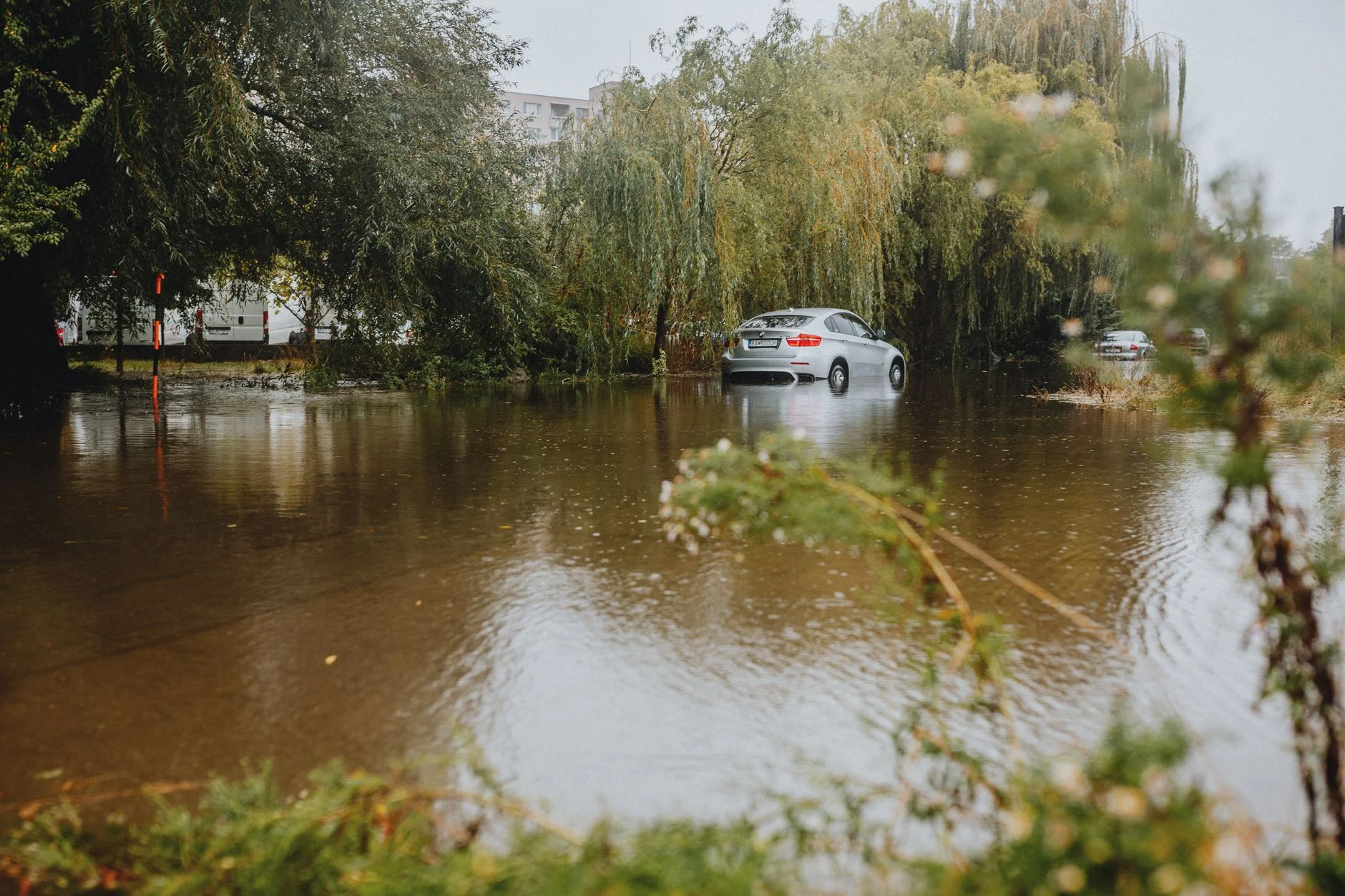 A car driving through a flooded street after heavy rain