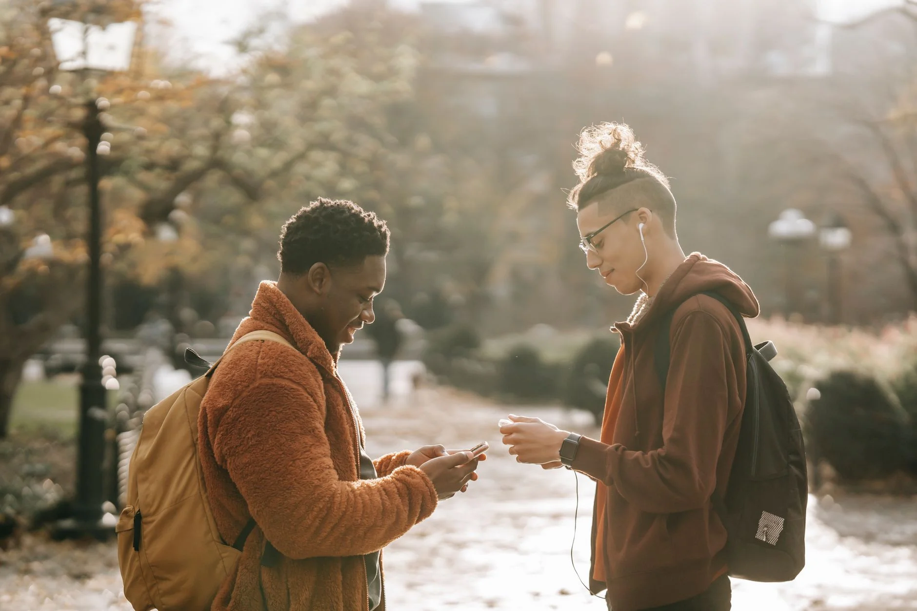 Two young friends standing in a park looking at a smartphone together