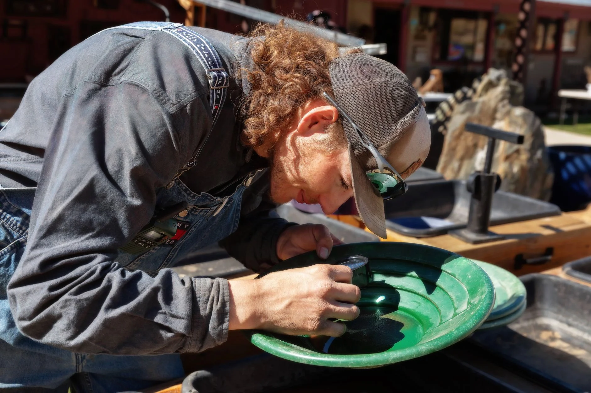 Prospector panning for gold, swirling gravel and water in a green gold pan