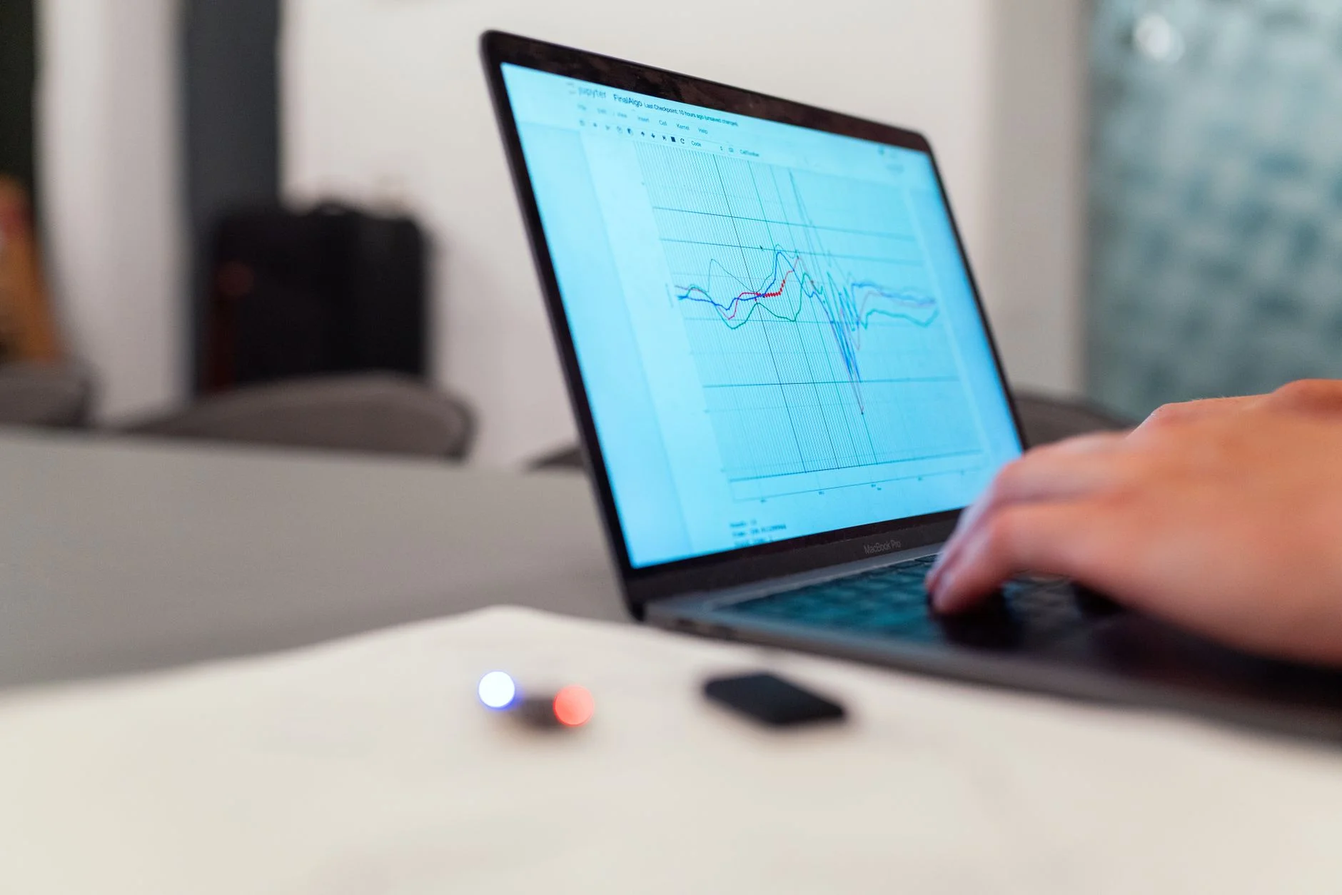 A person typing on a laptop that shows a line graph of data traces