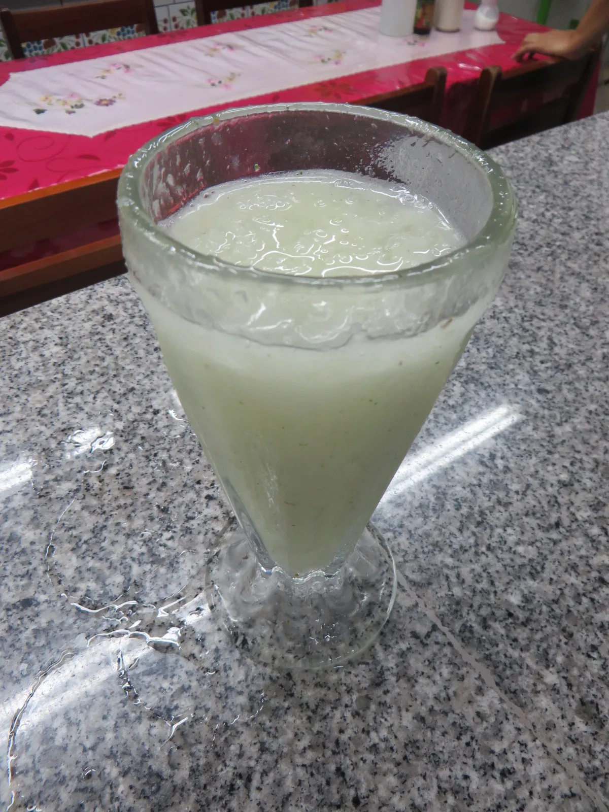 A glass of pale, creamy soursop juice on a granite counter
