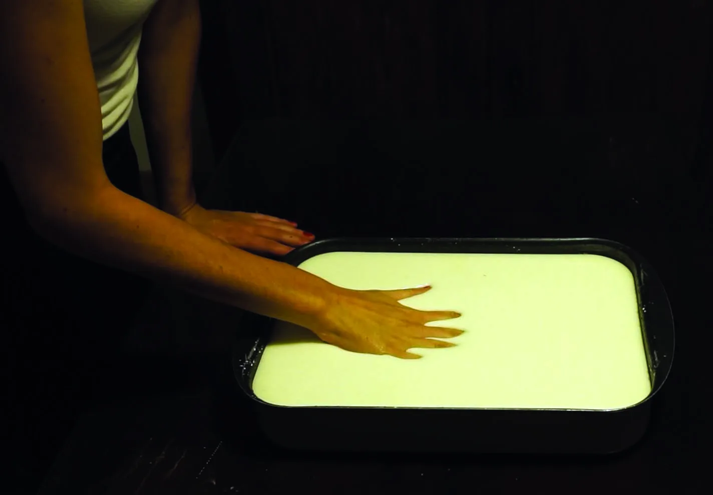 A flat hand sinking slowly into the same pale cornflour mixture