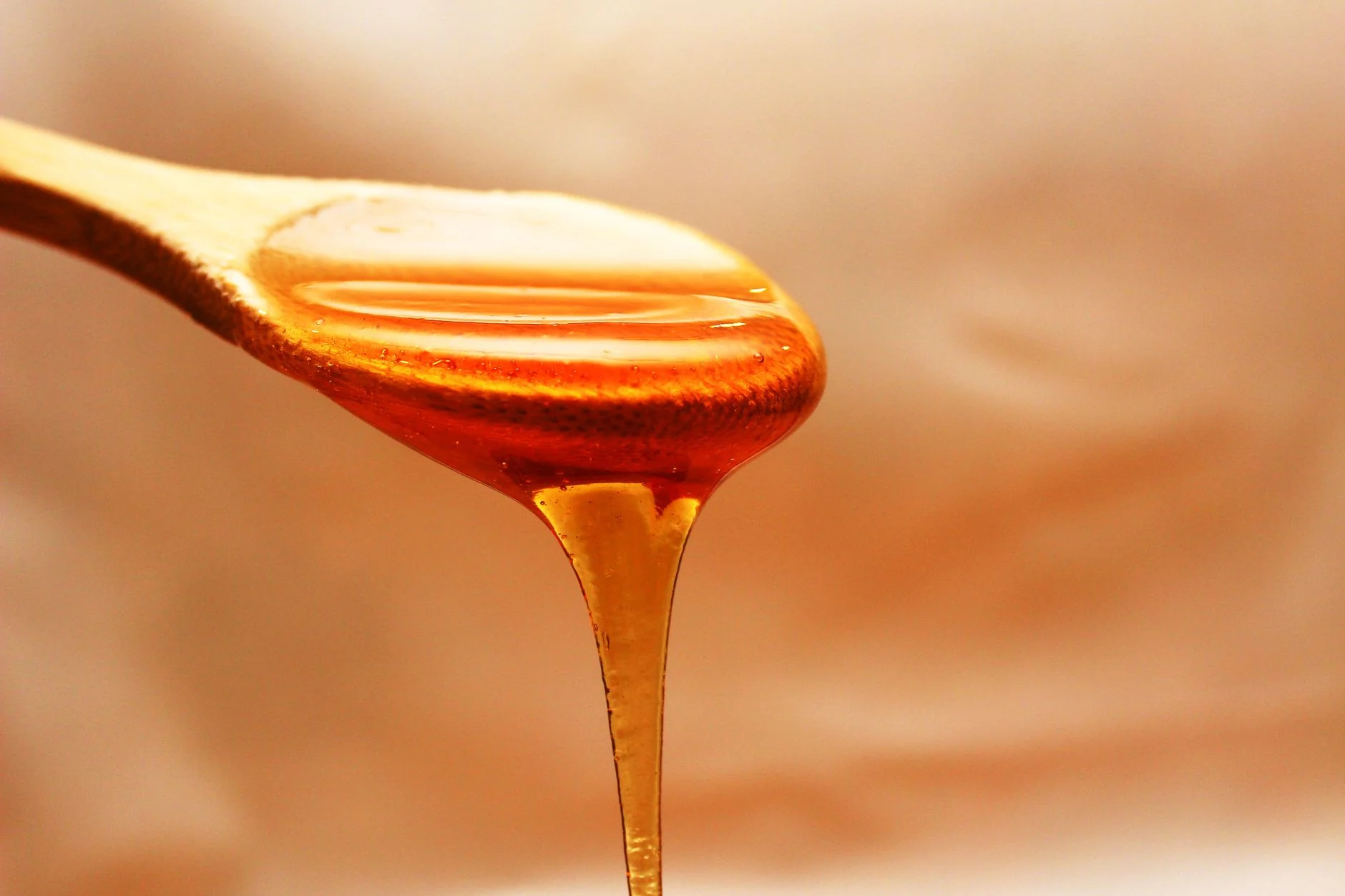 Golden honey dripping from a wooden spoon
