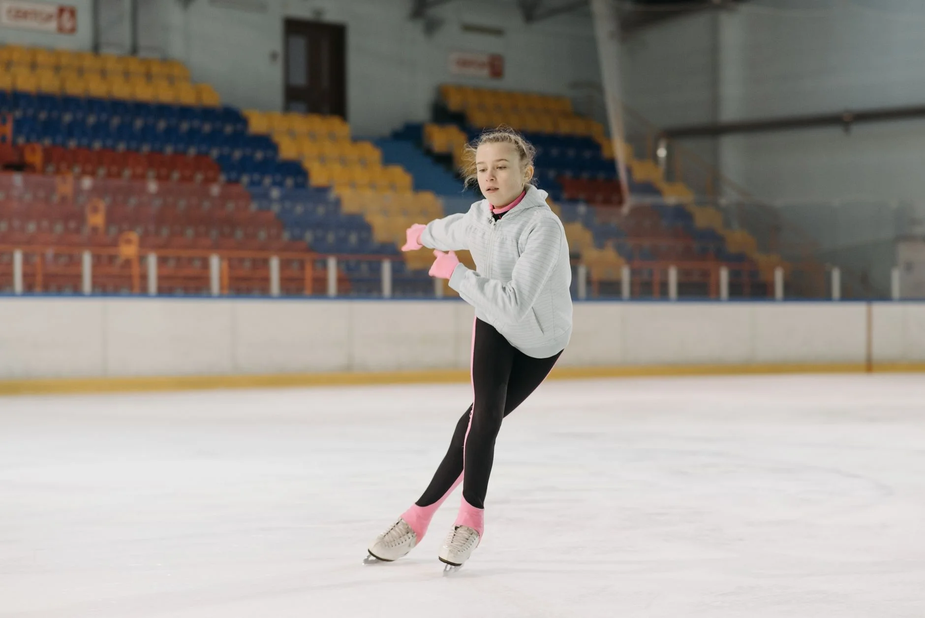 A young figure skater gliding across an indoor ice rink