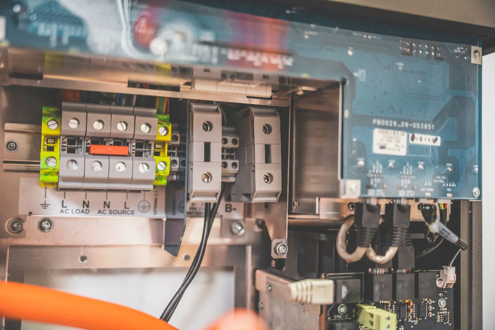 Inside an inverter unit: rows of wiring terminals labelled AC load and AC source, a circuit board and cables