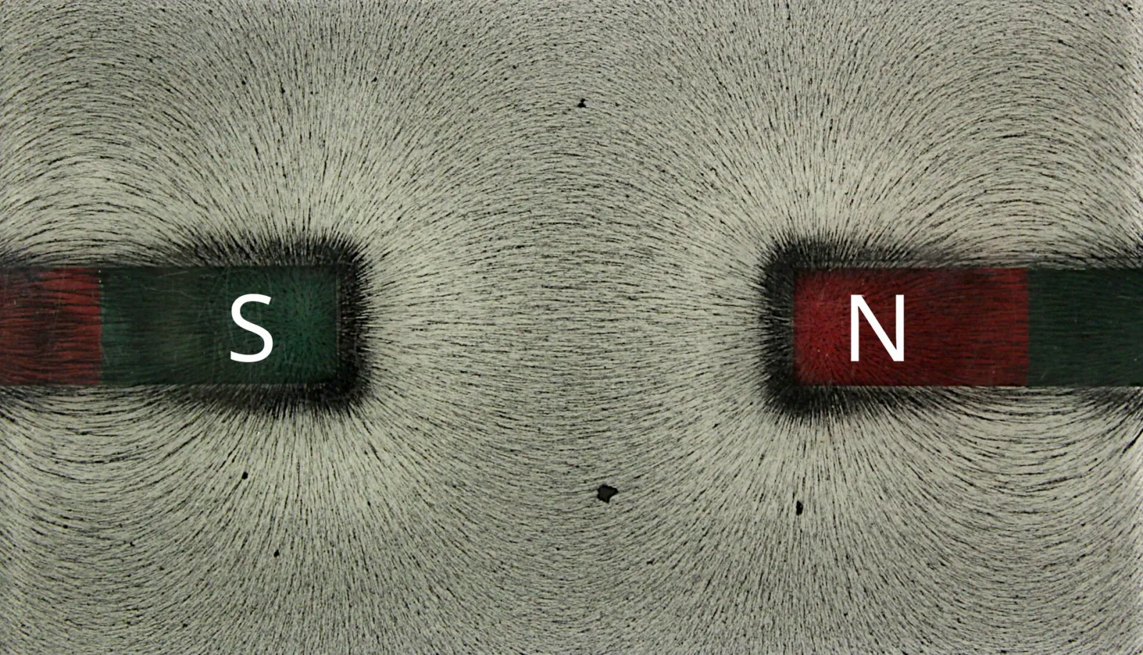 Iron filings forming lines that run straight across the gap between the S pole of one bar magnet and the N pole of another
