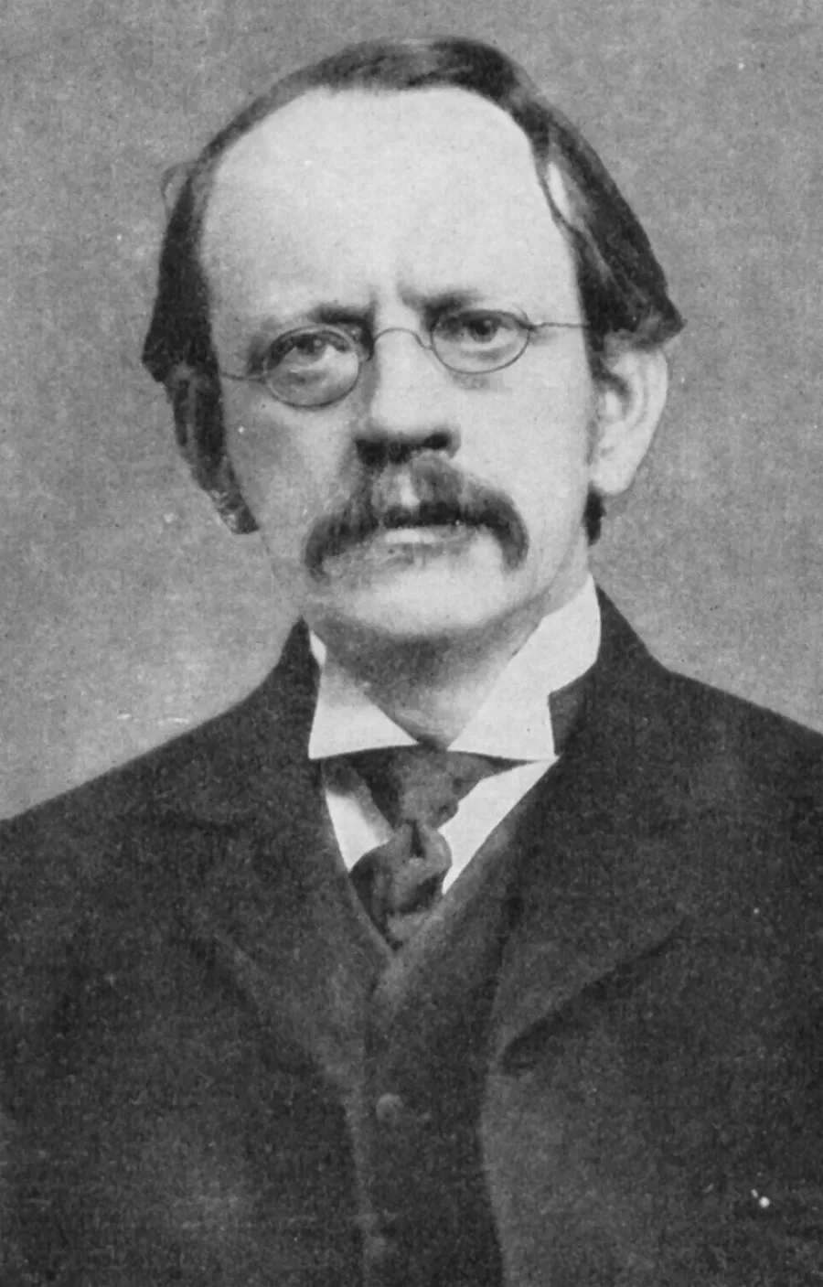 Black-and-white portrait photograph of physicist J. J. Thomson with round glasses and a moustache