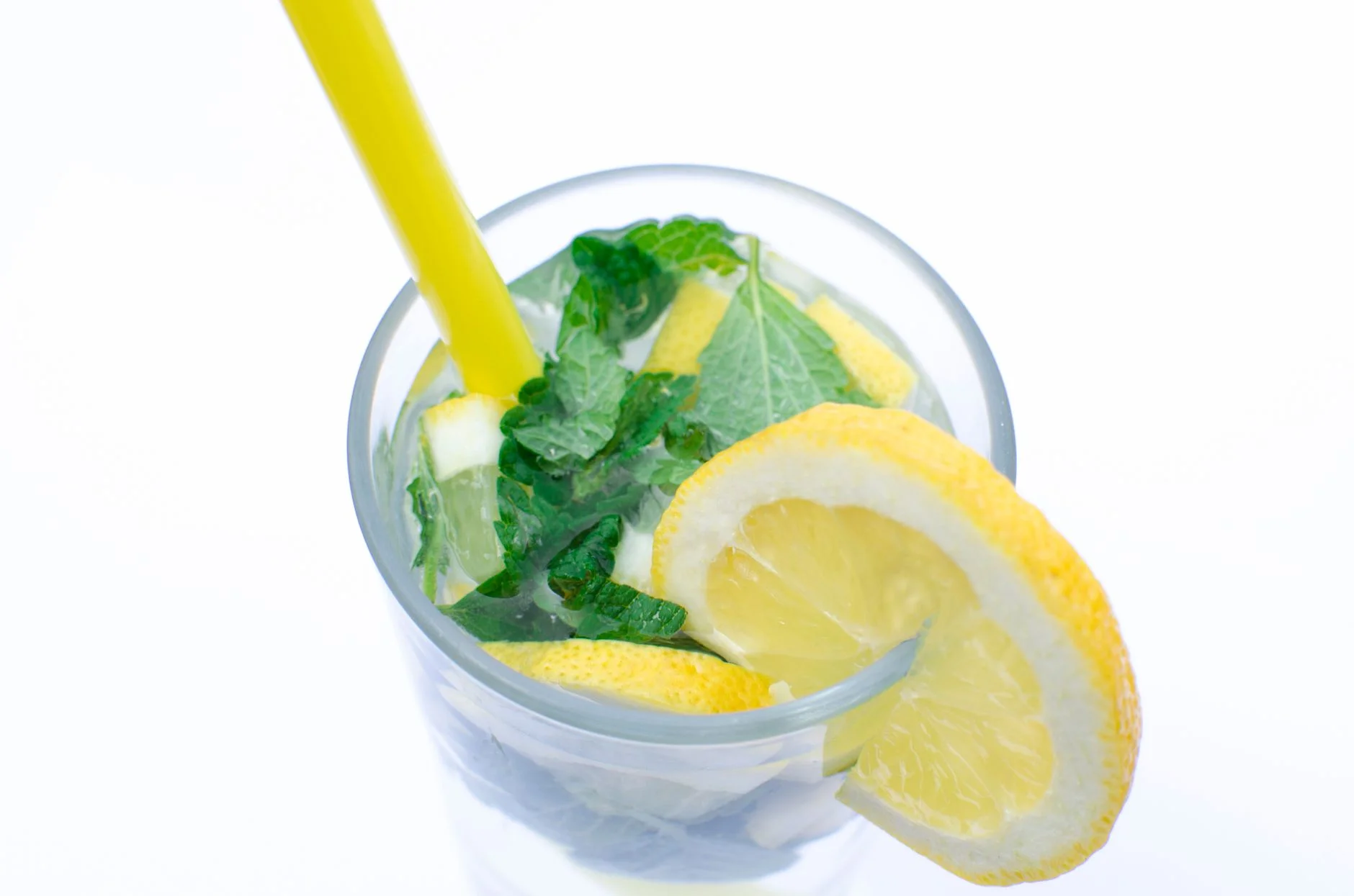 A glass of water with lemon slices, mint and ice