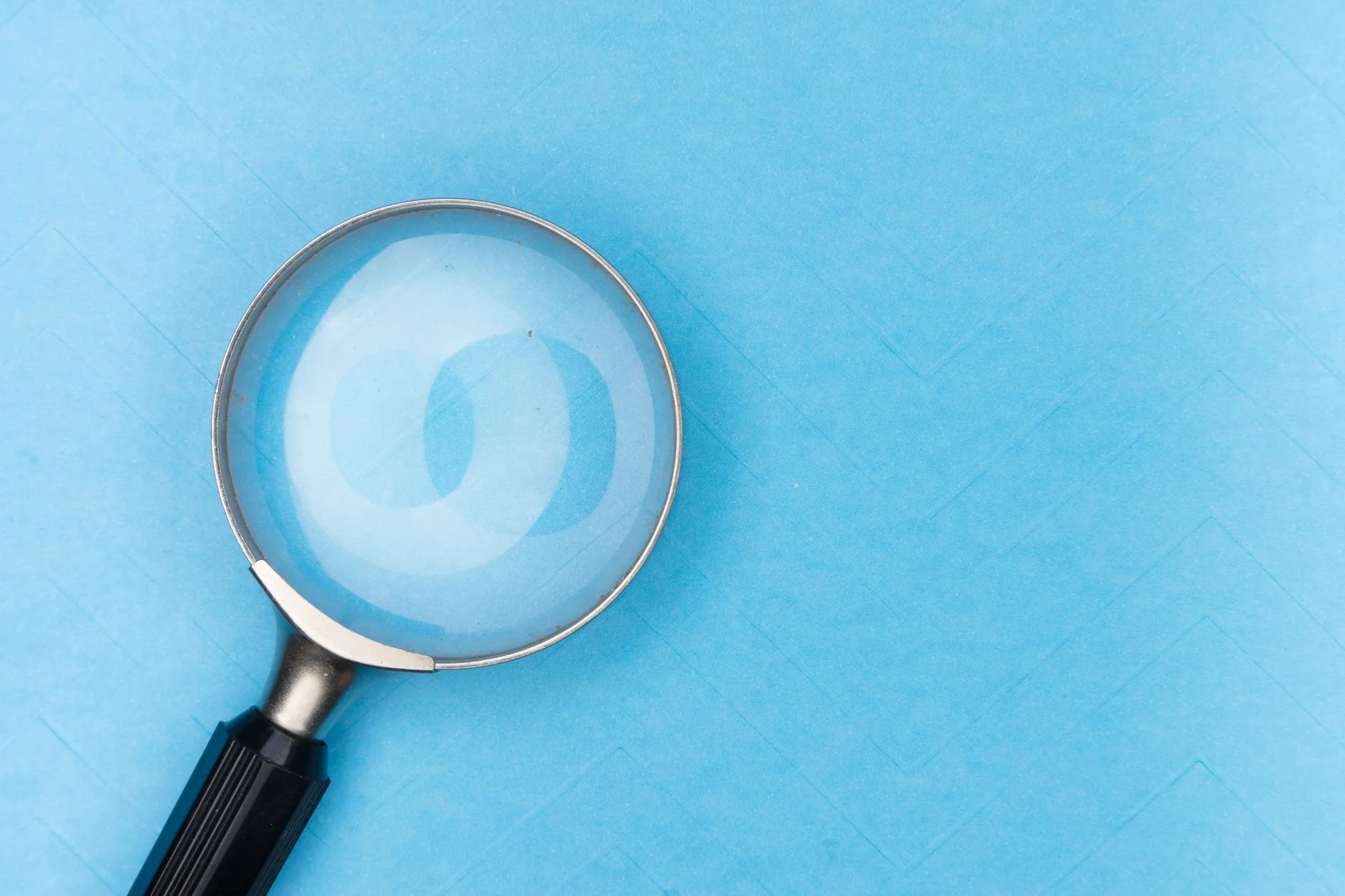 A magnifying glass lying on a pale blue surface