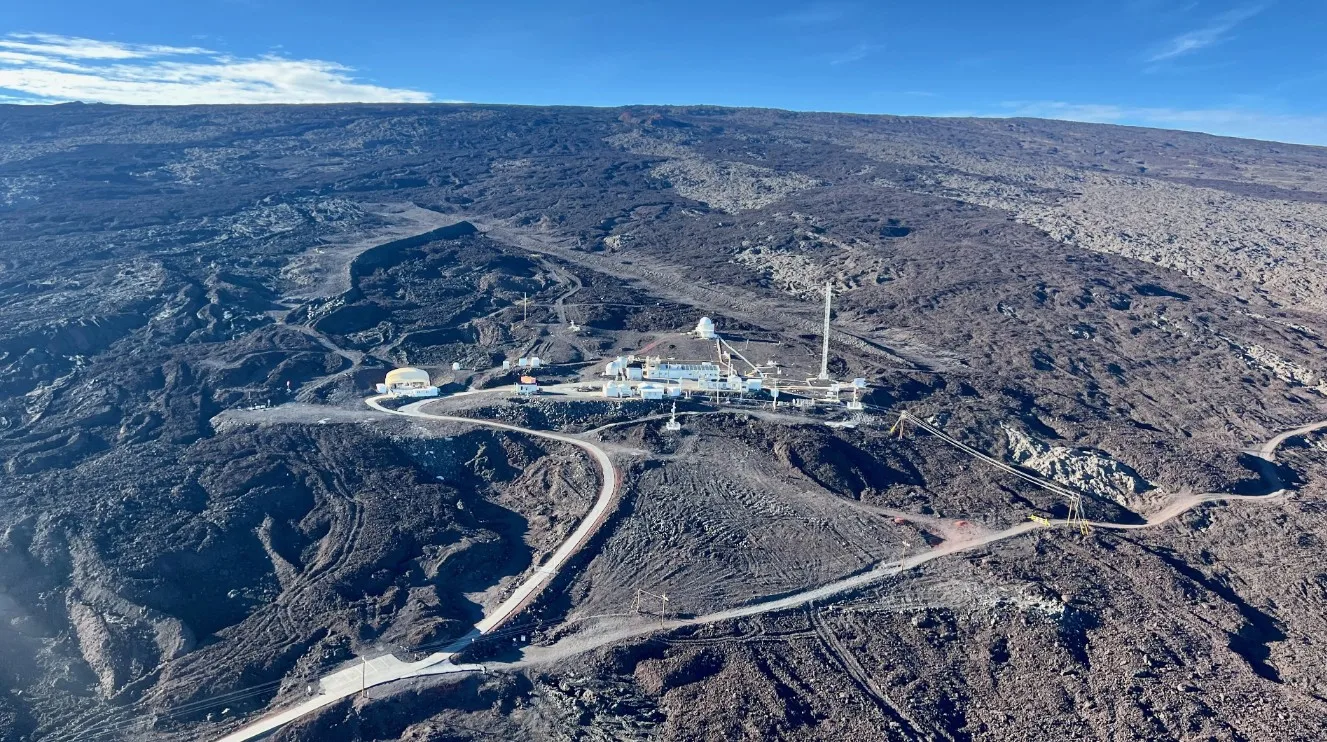 Aerial view of NOAA’s Mauna Loa Observatory, a cluster of white buildings on dark volcanic lava slopes in Hawaii