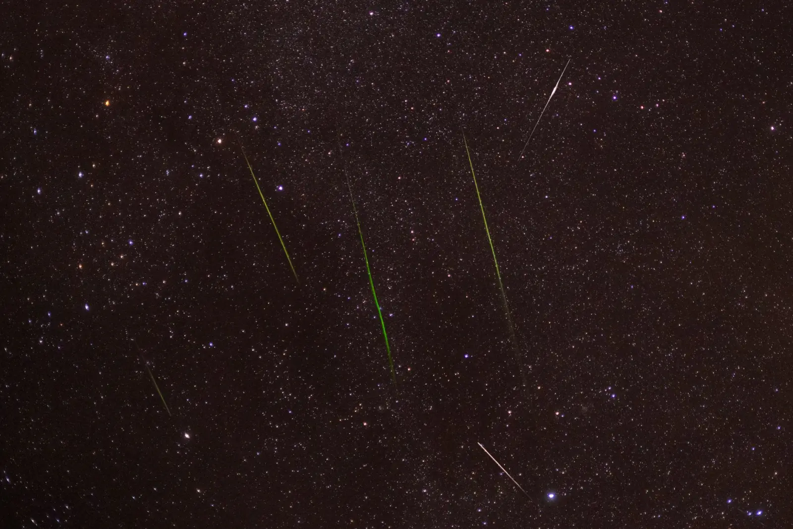 Several meteors streaking across a starry night sky during a meteor shower