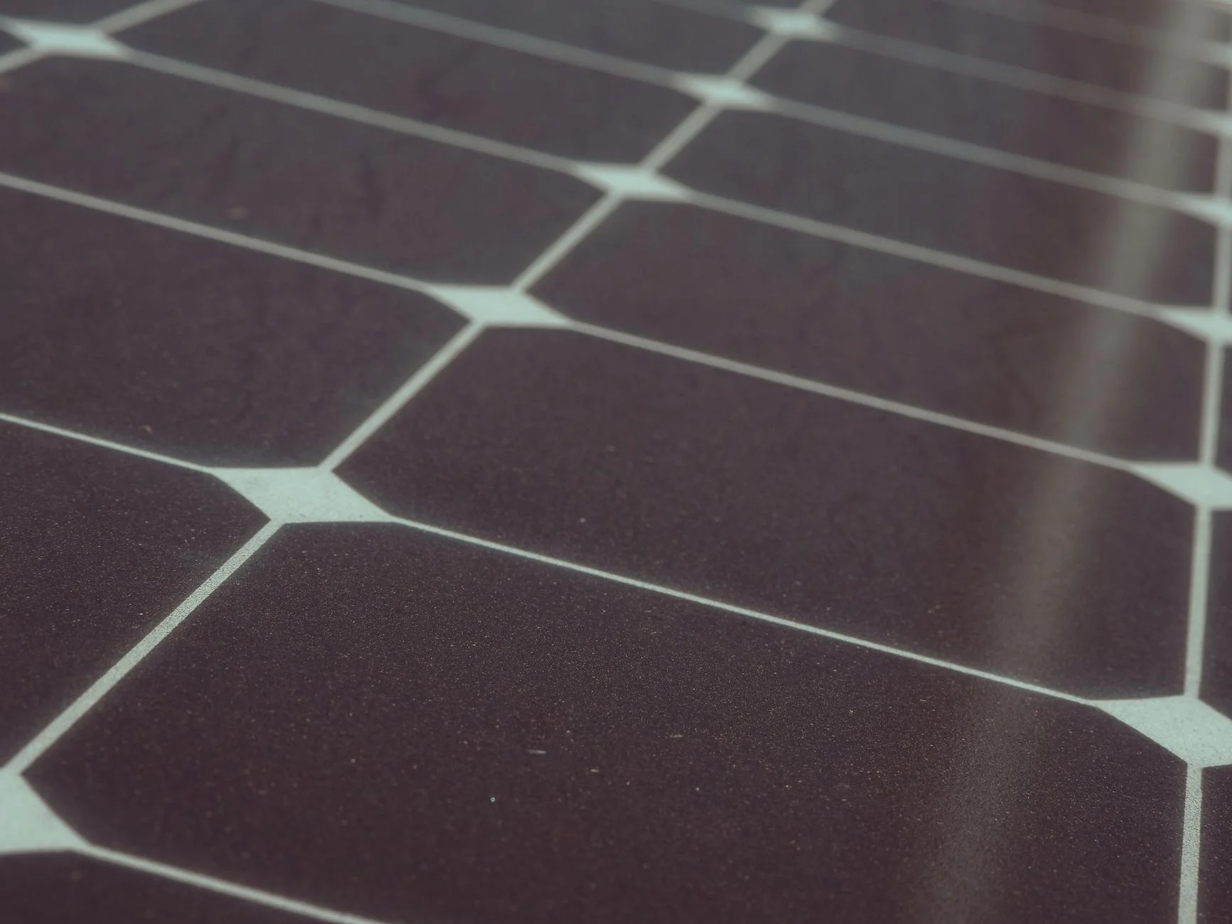 Close-up of dark monocrystalline solar cells with clipped corners and pale gaps between them
