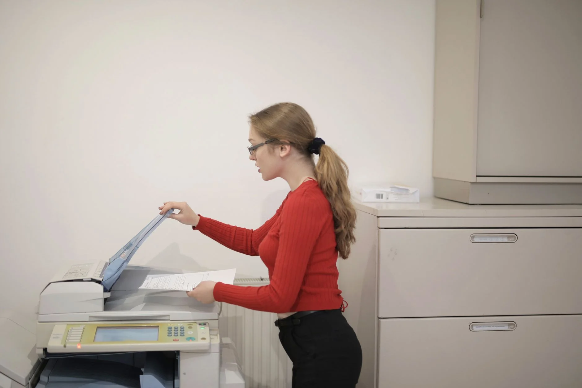 A woman placing a document into an office photocopier