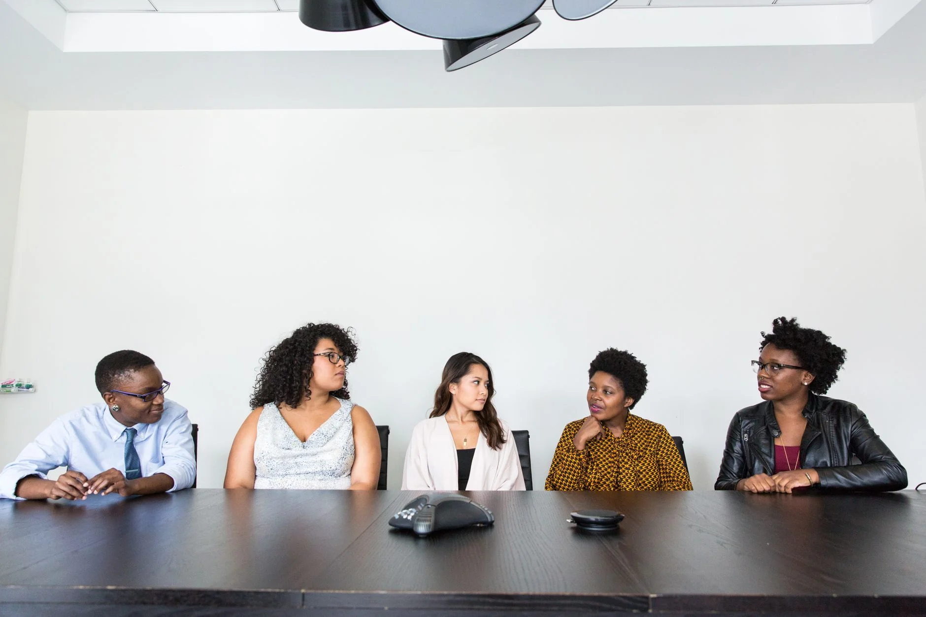 Five colleagues seated along a meeting table in a modern office