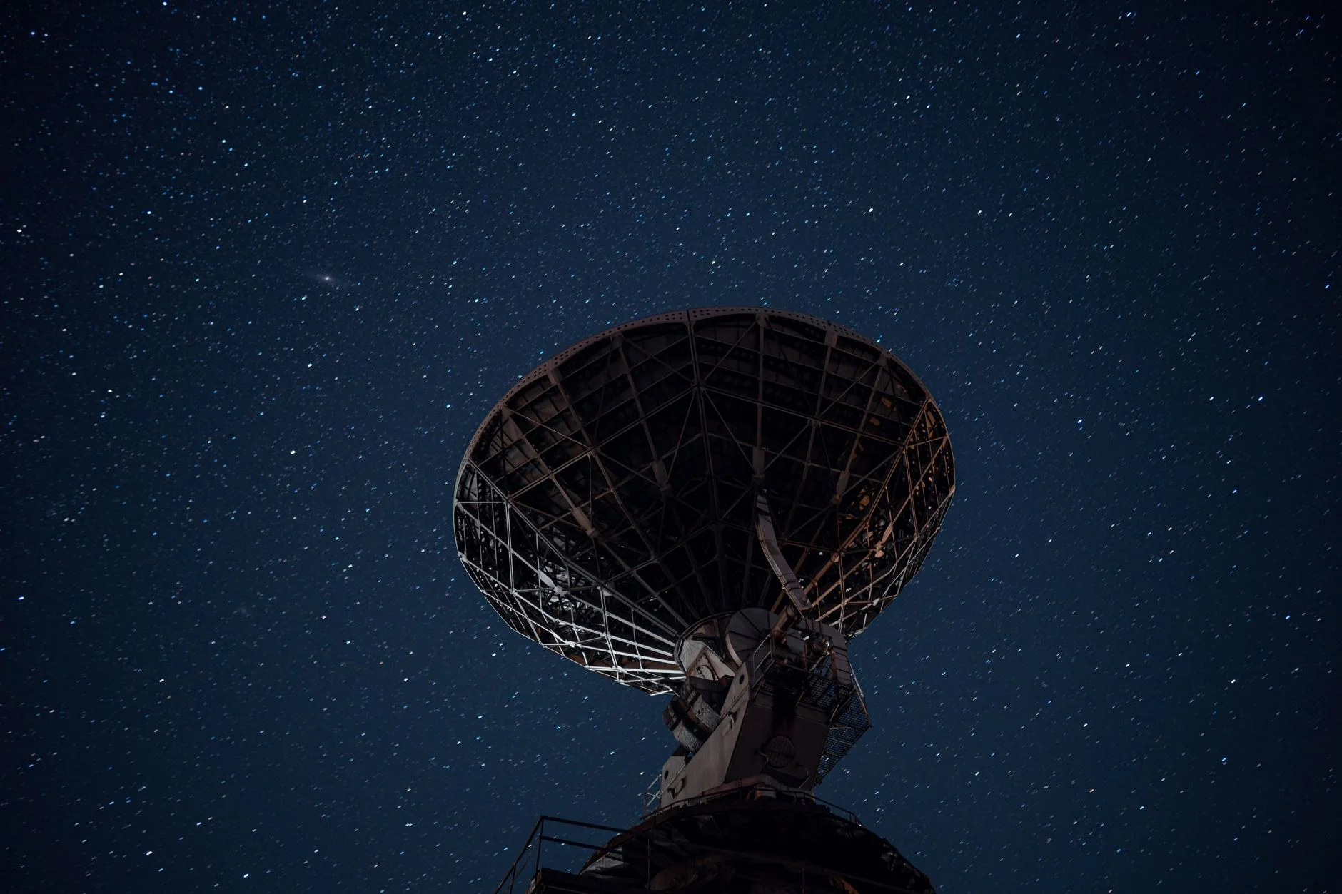 A radio telescope dish under a starry night sky