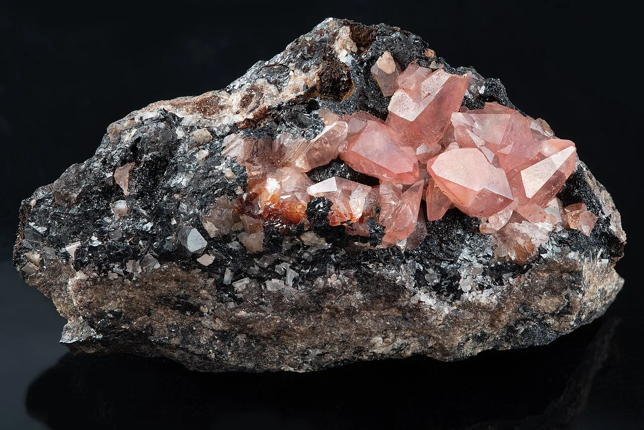 Pink rhodochrosite (manganese carbonate) crystals on dark rock from Peru