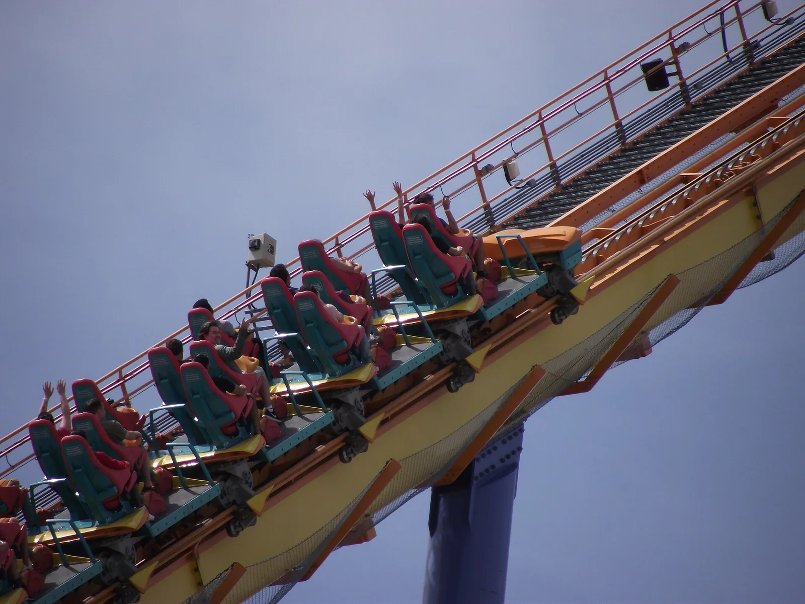 Roller coaster train climbing a steep lift hill with riders’ arms raised