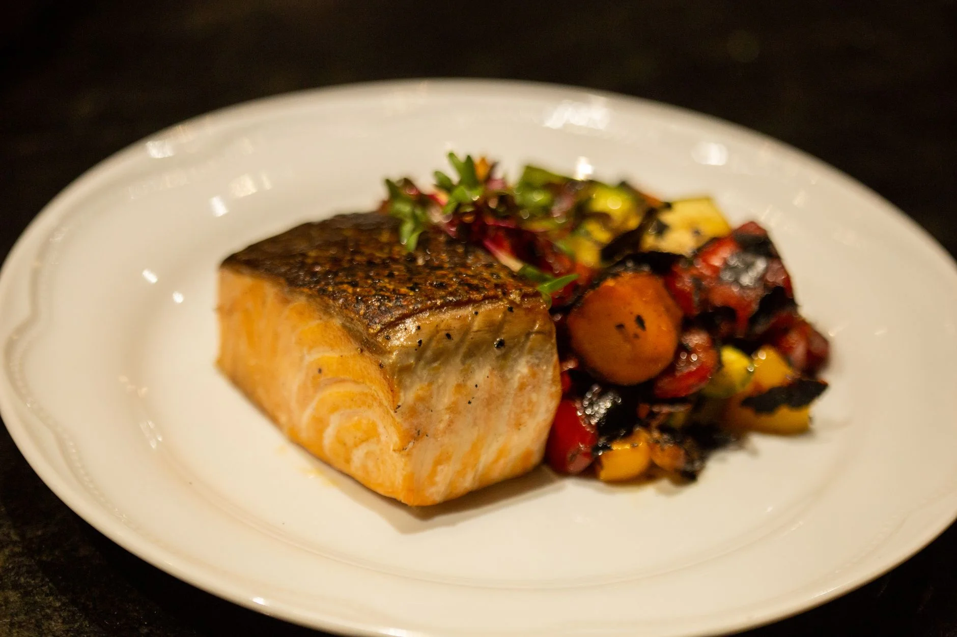 Grilled salmon fillet with colourful roasted vegetables on a white plate