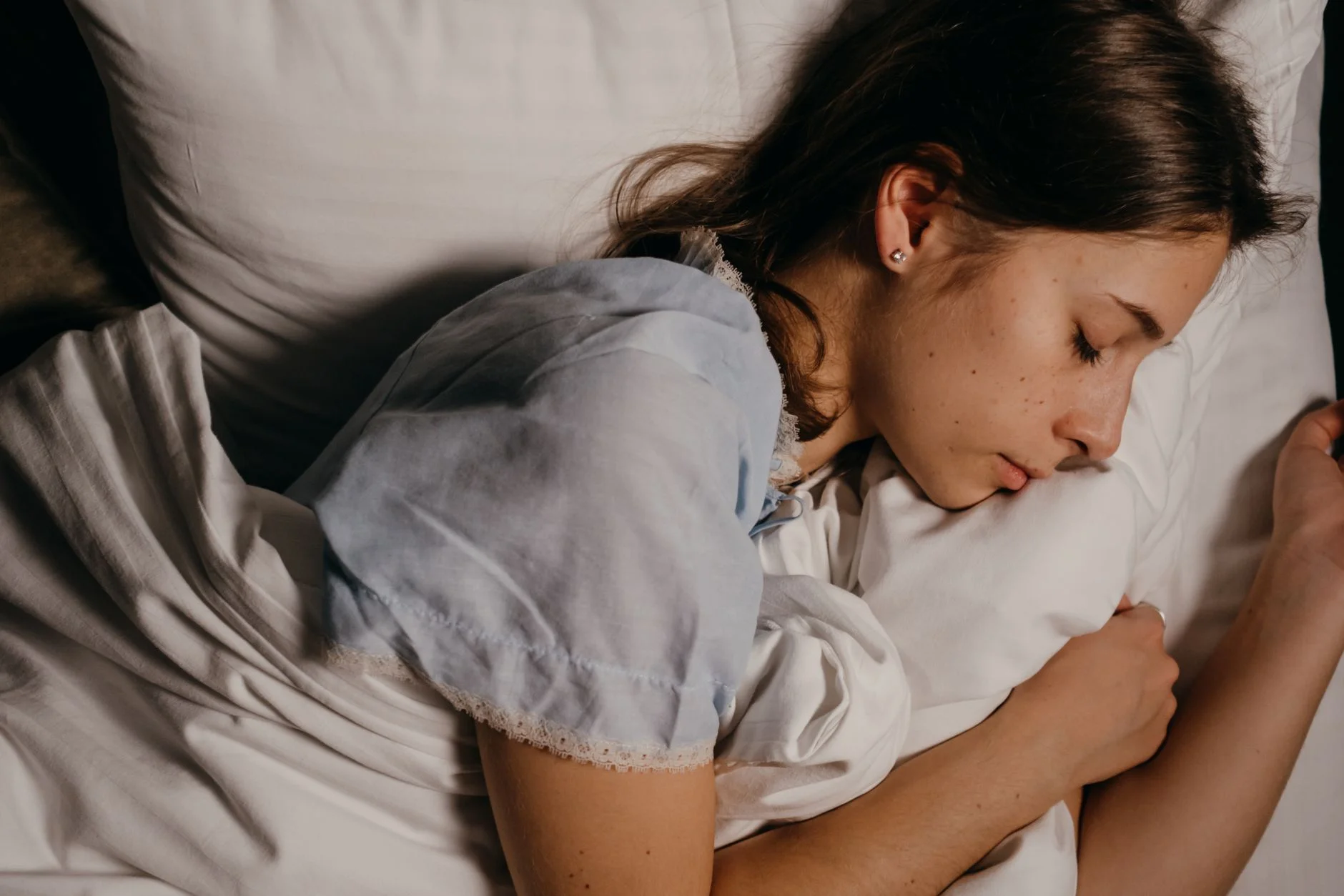 A young person asleep in bed with their head on a white pillow